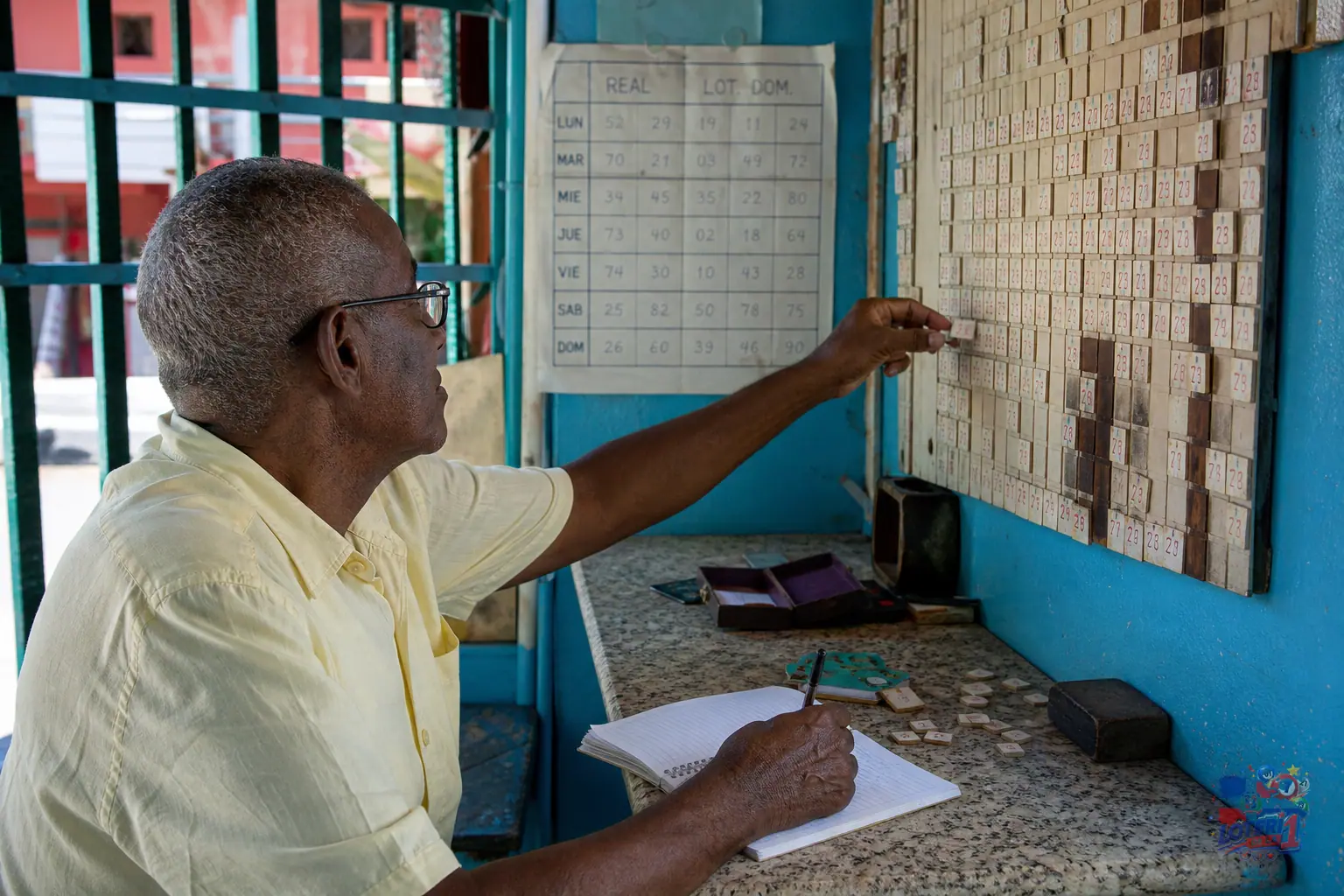 Terminal de banca dominicana con libreta de apuntes y pantalla de resultados desenfocada sin números legibles